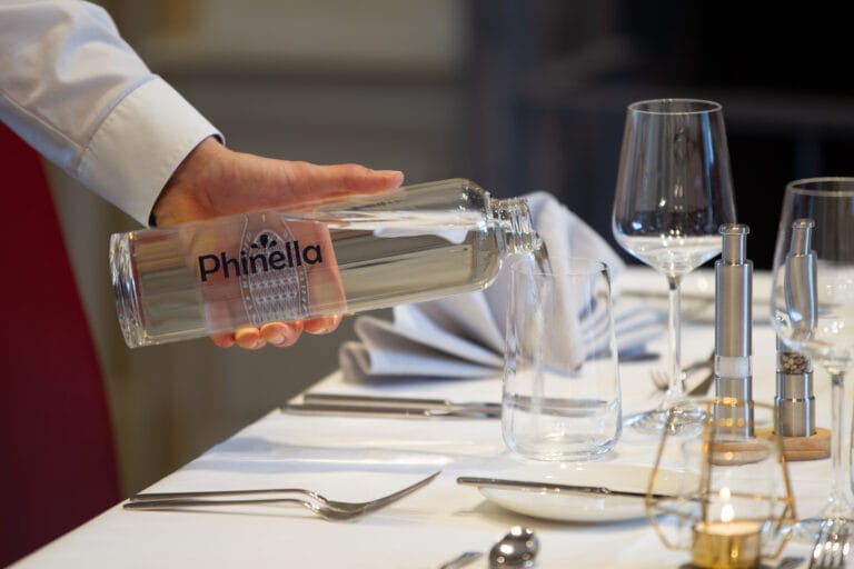 Phinella Wasser wird in ein Glas ausgeschenkt